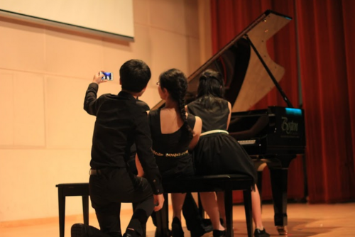 Kids take a selfie seated at a piano
